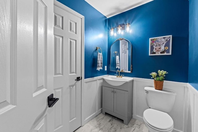 bathroom featuring a wainscoted wall, toilet, marble finish floor, and vanity