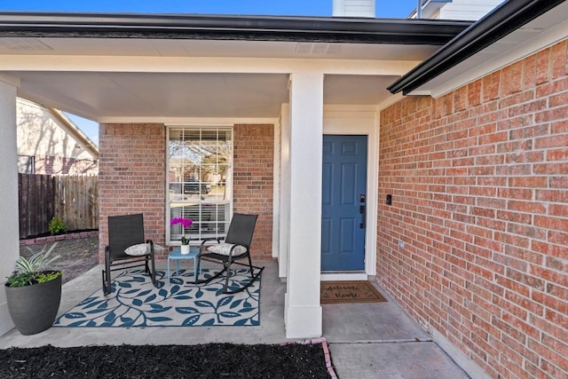 property entrance featuring brick siding and fence