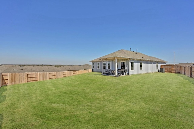 back of property with a fenced backyard, a lawn, board and batten siding, and central AC