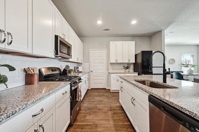 11724 Domenico Cv, Austin, TX 78747 - kitchen with stainless steel appliances, dark wood-type flooring, white cabinets, light stone countertops, and recessed lighting