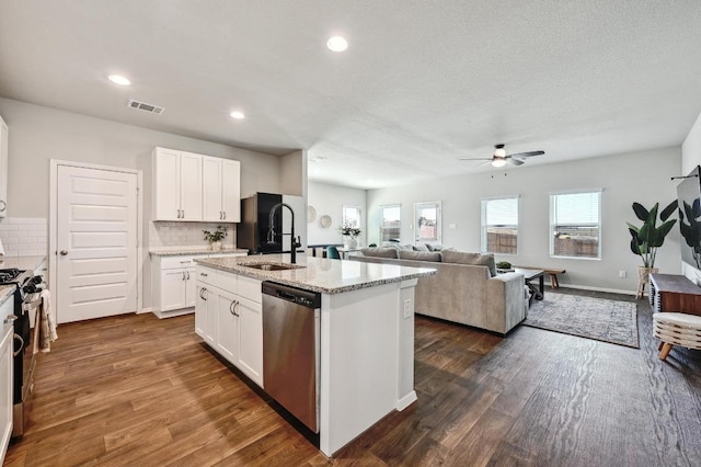 kitchen featuring visible vents, a kitchen island with sink, a sink, open floor plan, and appliances with stainless steel finishes