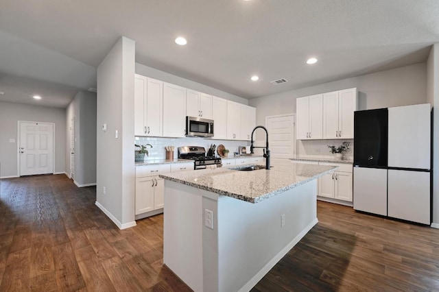 11724 Domenico Cv, Austin, TX 78747 - kitchen featuring appliances with stainless steel finishes, backsplash, a center island with sink, white cabinetry, and recessed lighting