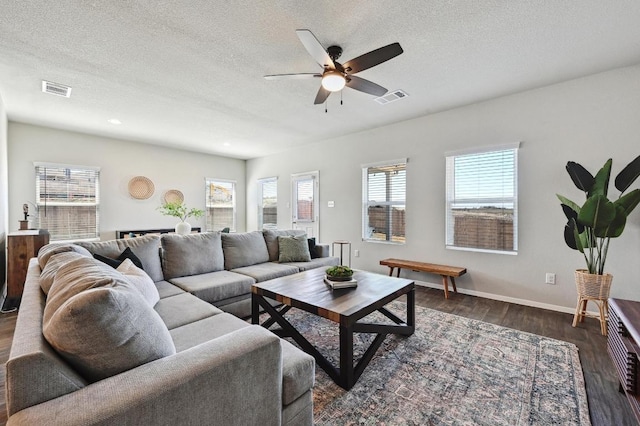 living area featuring visible vents, a healthy amount of sunlight, and dark wood-style flooring