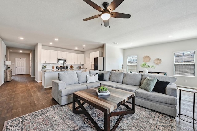 living room featuring recessed lighting, baseboards, a textured ceiling, and dark wood-style flooring