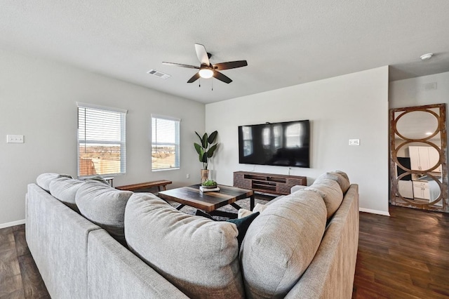 living room with a ceiling fan, baseboards, visible vents, dark wood-type flooring, and a textured ceiling