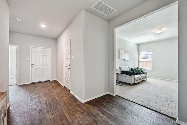 foyer entrance with dark wood finished floors, baseboards, and visible vents