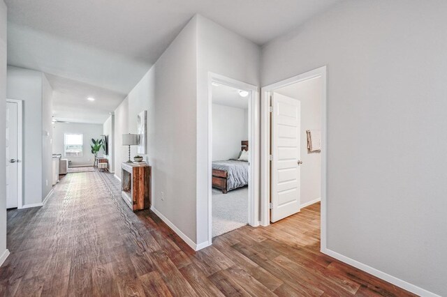 hallway with dark wood-type flooring and baseboards