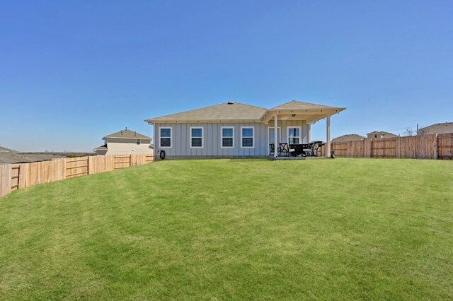 back of property with a lawn, board and batten siding, and a fenced backyard