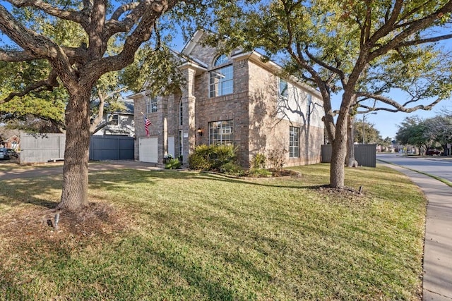 traditional-style home featuring brick siding, an attached garage, a front yard, and fence