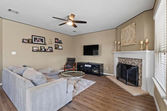 living room with visible vents, a ceiling fan, wood finished floors, a fireplace, and baseboards