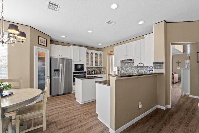 kitchen featuring a healthy amount of sunlight, stainless steel fridge, wall oven, and black microwave