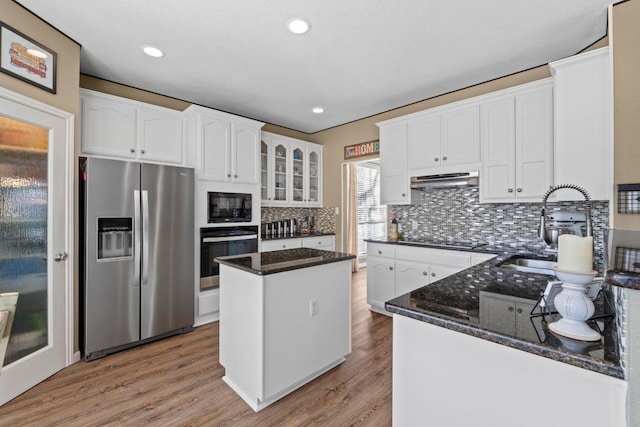 kitchen with black appliances, a sink, dark stone counters, white cabinets, and light wood finished floors