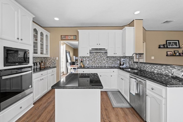 kitchen featuring a kitchen island, a peninsula, exhaust hood, black appliances, and a sink