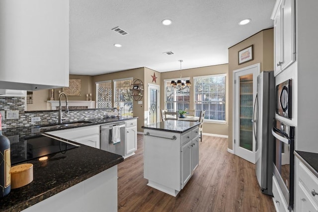 kitchen with stainless steel appliances, backsplash, visible vents, and dark wood-style floors