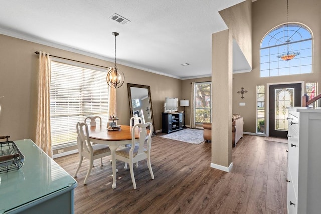 dining room with crown molding, wood finished floors, visible vents, and a chandelier