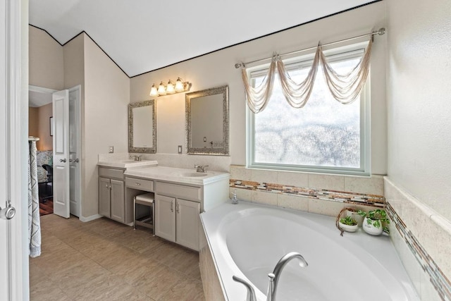 full bath with a sink, plenty of natural light, a garden tub, and double vanity