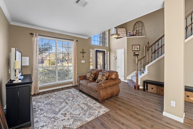 living area with wood finished floors, visible vents, baseboards, stairs, and crown molding