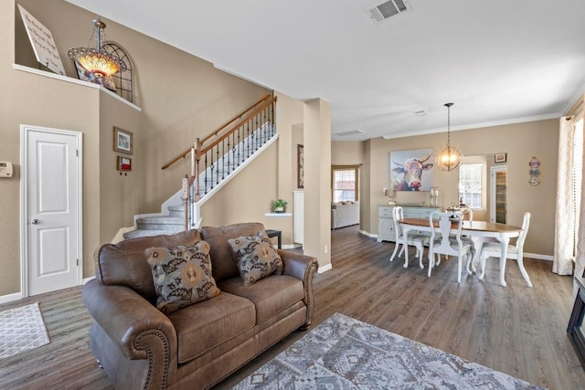 living area with visible vents, stairs, baseboards, and wood finished floors