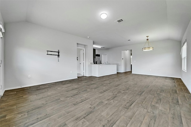 unfurnished living room featuring visible vents, baseboards, lofted ceiling, and wood finished floors