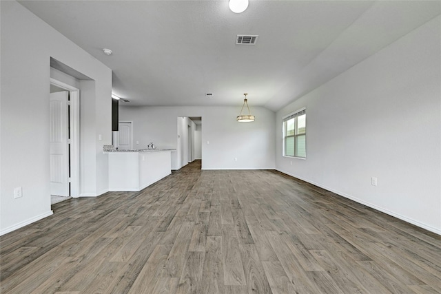 unfurnished living room with visible vents, baseboards, and wood finished floors