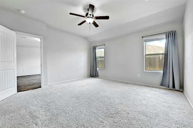 spare room featuring lofted ceiling, a ceiling fan, a wealth of natural light, and carpet floors