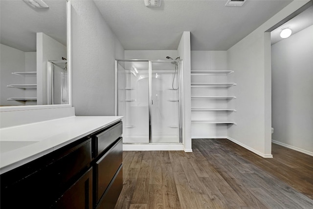 full bath featuring baseboards, vanity, wood finished floors, and a shower stall