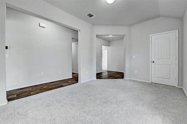 spare room with visible vents, baseboards, carpet flooring, and vaulted ceiling