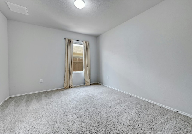 spare room featuring visible vents, carpet floors, a textured ceiling, and baseboards