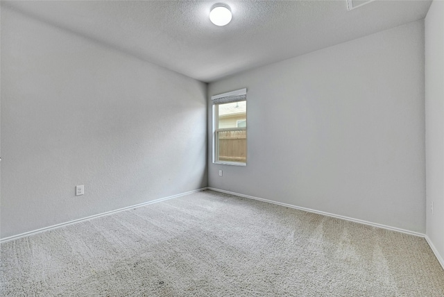 spare room featuring baseboards, a textured ceiling, and carpet flooring