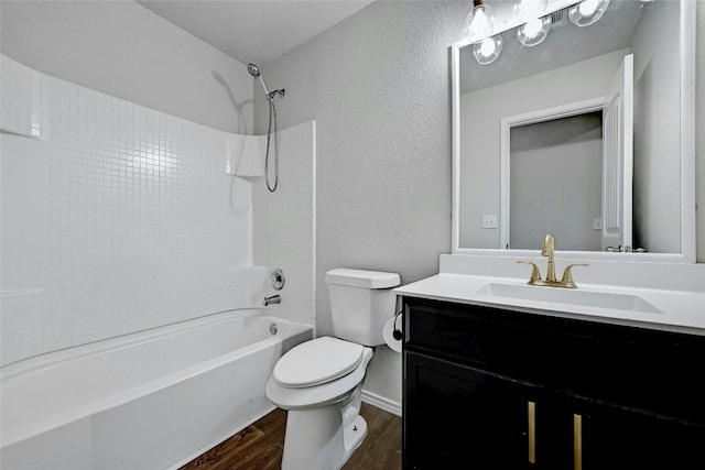 bathroom featuring vanity, wood finished floors,  shower combination, toilet, and a textured wall