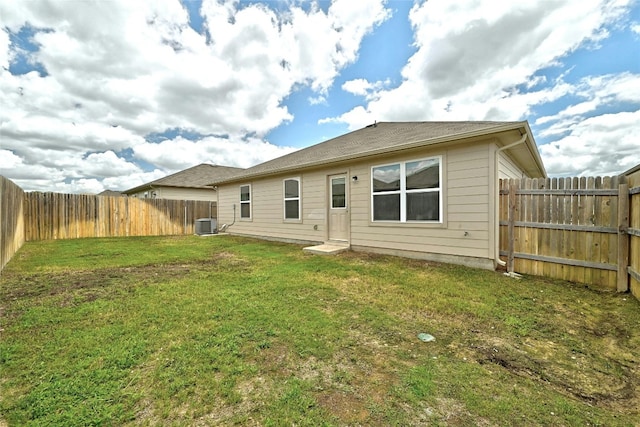 rear view of house with a lawn, cooling unit, and a fenced backyard