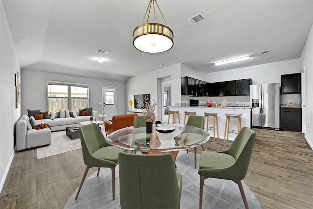 dining room featuring visible vents, baseboards, and light wood-style flooring