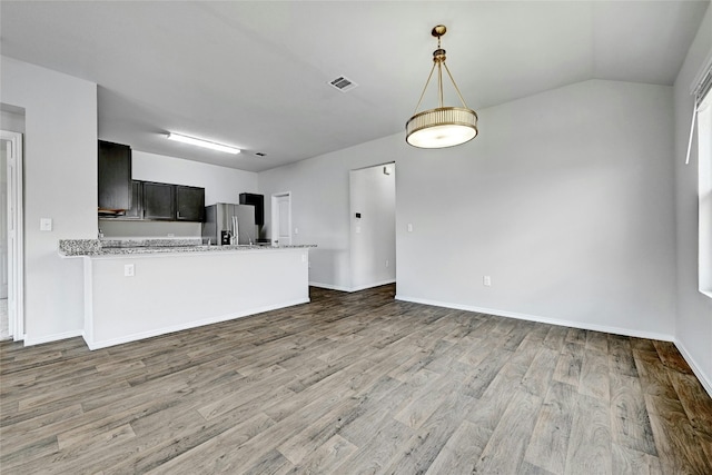 5800 Shanjia Dr, Austin, TX 78724 - kitchen featuring stainless steel refrigerator with ice dispenser, wood finished floors, decorative light fixtures, and vaulted ceiling