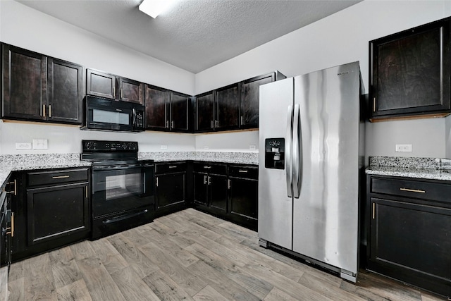 kitchen featuring light stone countertops, light wood-style floors, black appliances, and a textured ceiling