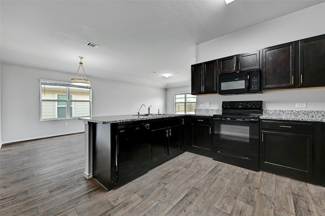 kitchen with light wood finished floors, black appliances, light stone counters, and a sink