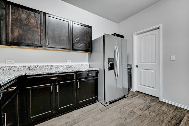 kitchen with baseboards, light stone countertops, stainless steel fridge with ice dispenser, and light wood finished floors