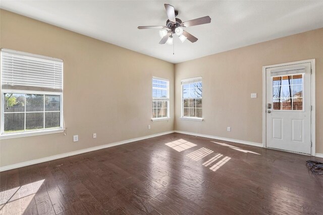 empty room with ceiling fan, baseboards, and dark wood-style floors