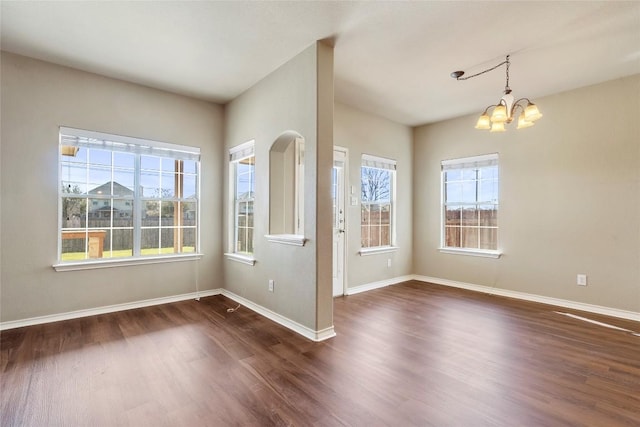 spare room with dark wood-style floors, a notable chandelier, and baseboards