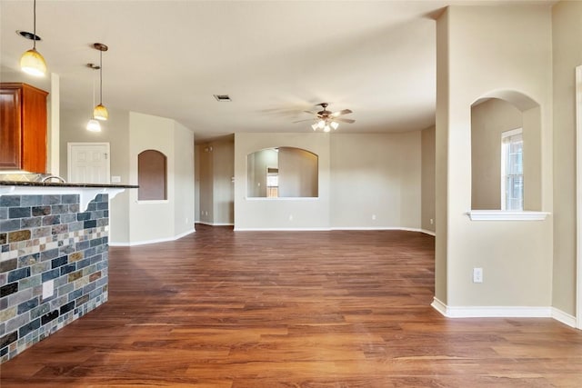 unfurnished living room with visible vents, wood finished floors, baseboards, and ceiling fan