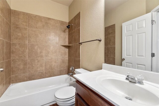 full bath featuring vanity, toilet,  shower combination, and a textured wall