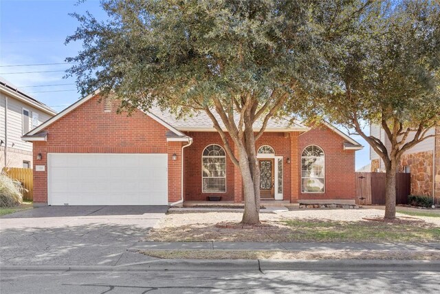 view of front of home with aphalt driveway, brick siding, a garage, and fence