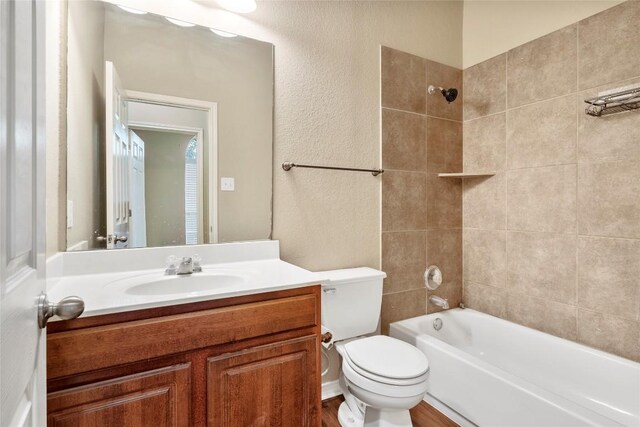 bathroom featuring tub / shower combination, toilet, vanity, and a textured wall