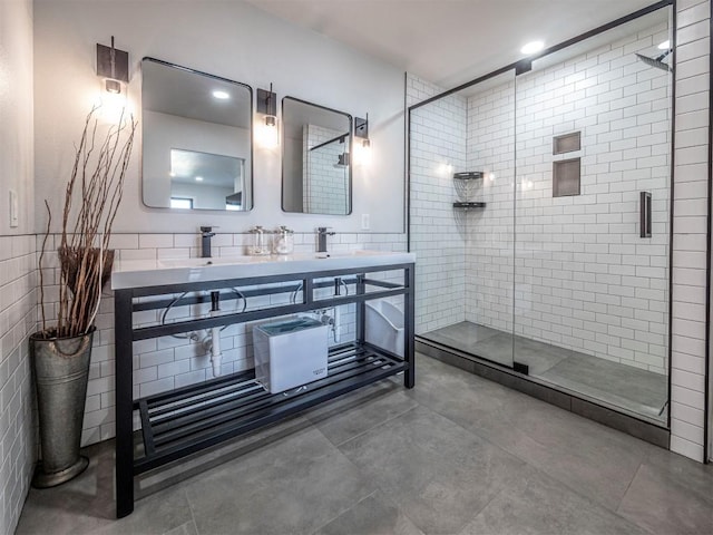 bathroom featuring a sink, a stall shower, tile walls, and double vanity