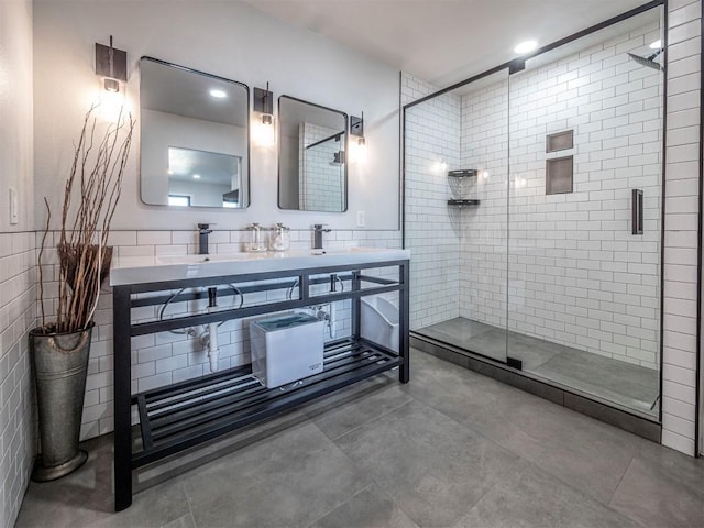 bathroom featuring a shower stall, tile walls, double vanity, and recessed lighting