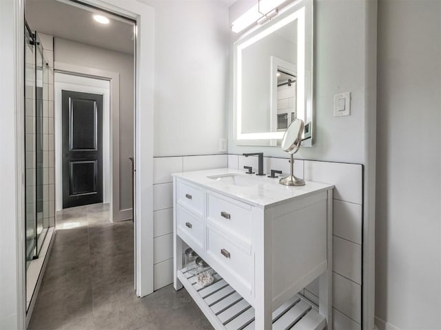 bathroom with vanity, concrete flooring, and a shower