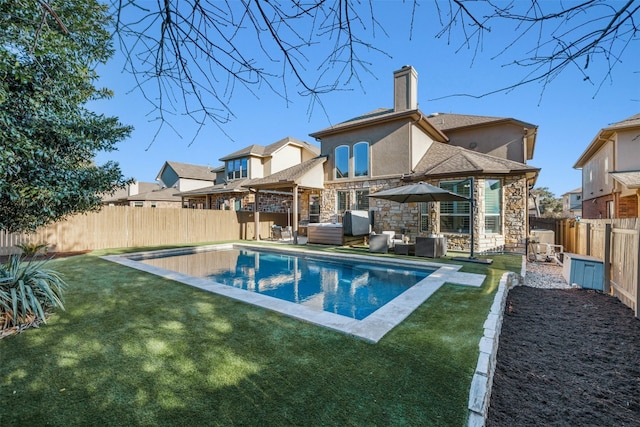 rear view of house with stucco siding, a lawn, outdoor lounge area, a fenced backyard, and stone siding