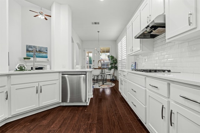 kitchen with visible vents, under cabinet range hood, dark wood finished floors, light countertops, and decorative backsplash