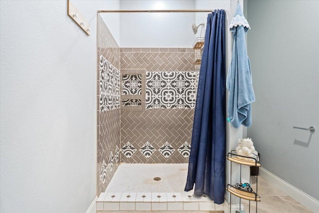 full bathroom featuring tile patterned flooring, baseboards, and tiled shower