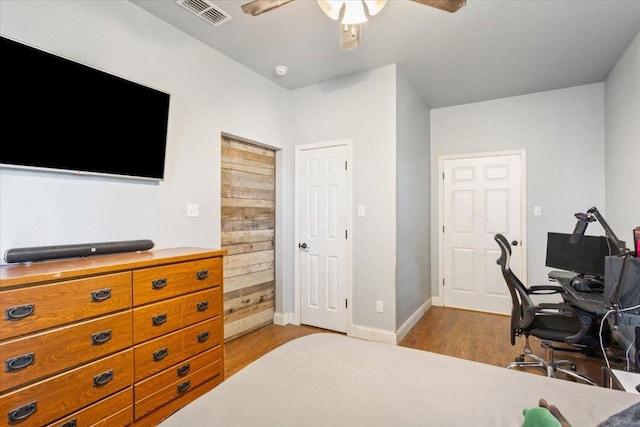 bedroom featuring ceiling fan, visible vents, baseboards, and wood finished floors