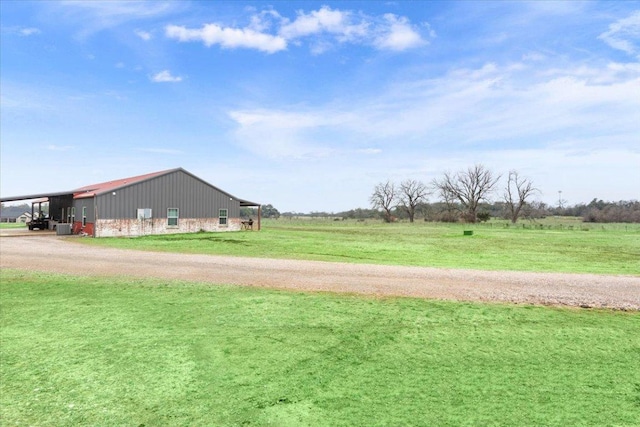 view of yard with an outbuilding, a rural view, and dirt driveway